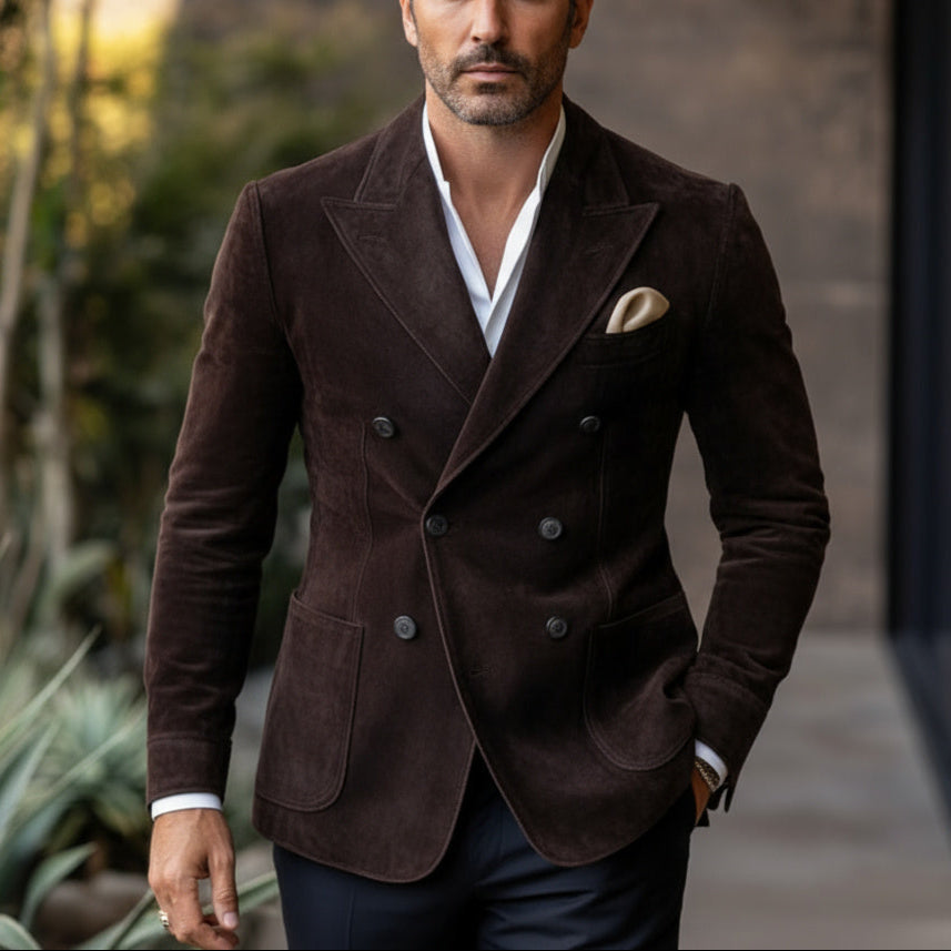 Man wearing a brown blazer with plants and a building in the background