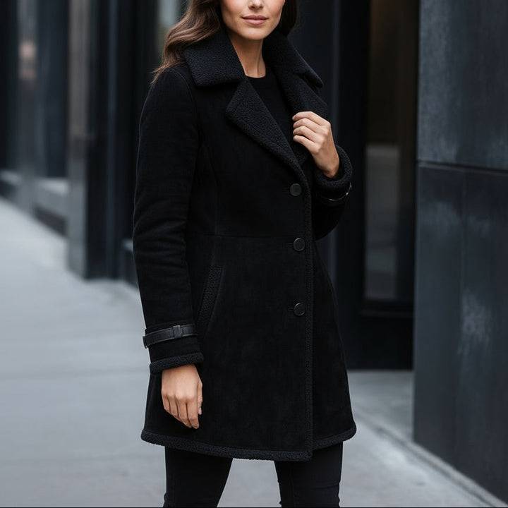 Woman wearing a black coat standing on a city street.