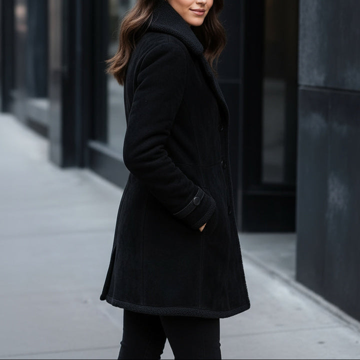 Woman wearing a black coat standing on a city street.